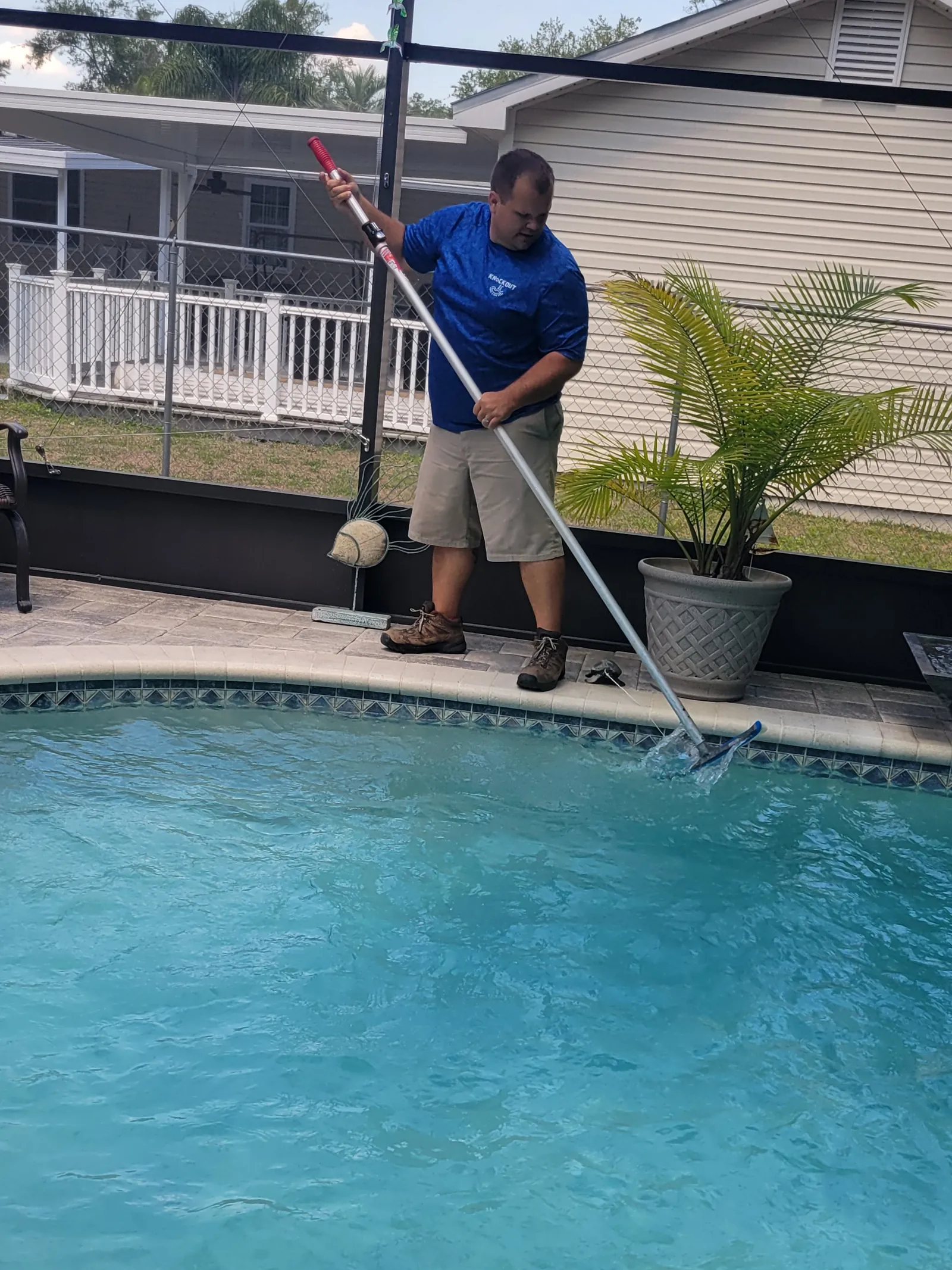 Brent, owner of Knockout Pool & Spa Care, brushing a screened-in pool in Brooksville, FL