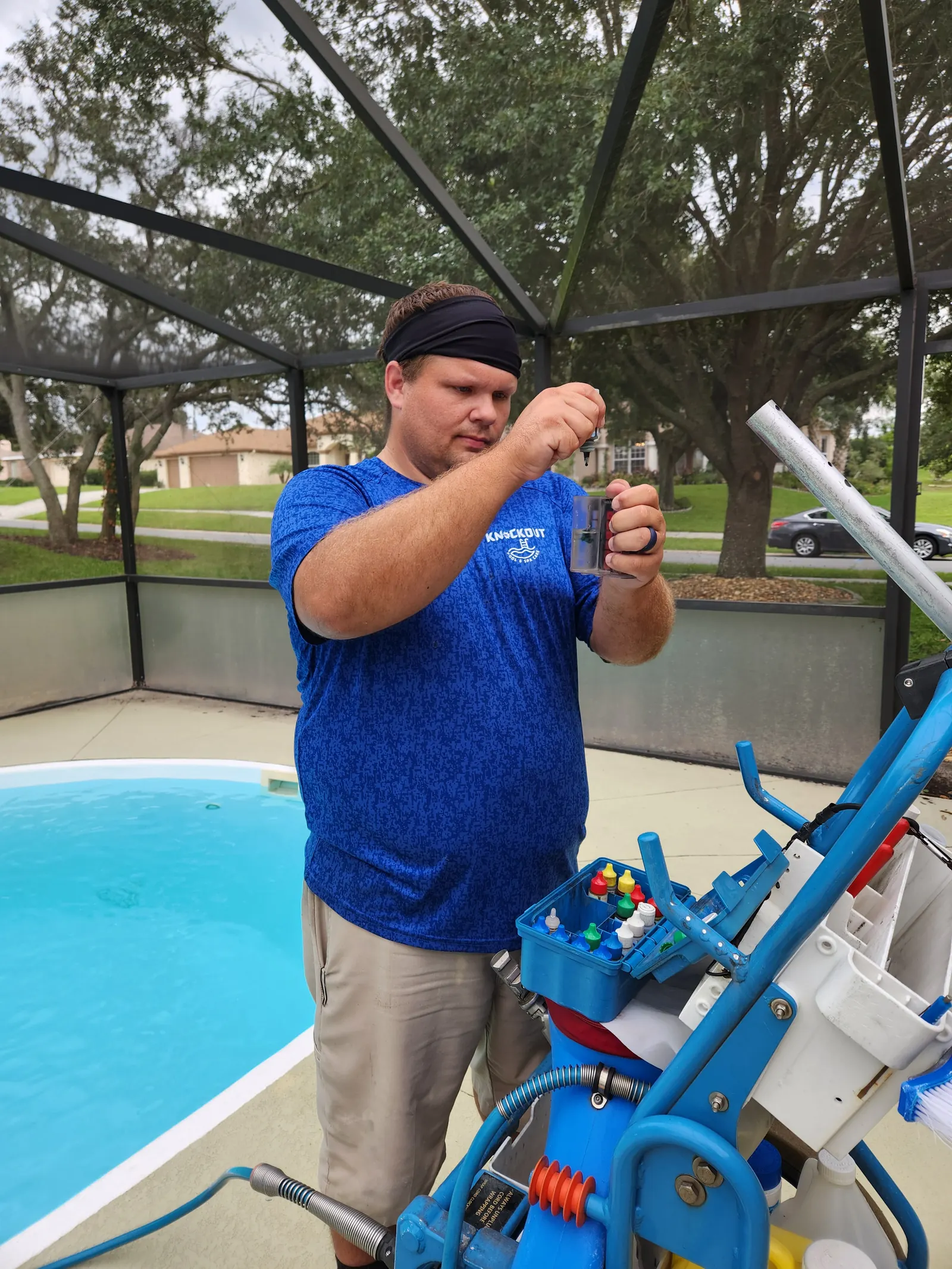 Brent from Knockout Pool & Spa Care testing pool water with a reagent kit beside a Spring Hill pool